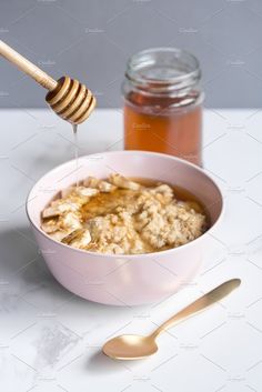 a bowl of oatmeal with honey and spoon