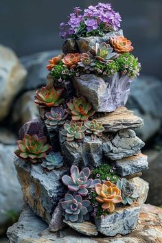 there are many succulents growing out of the rocks on this rock stack