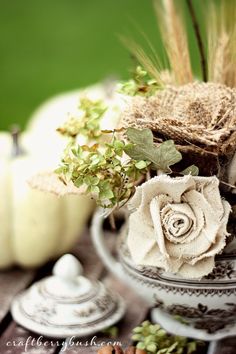 a vase filled with flowers sitting on top of a wooden table next to white pumpkins