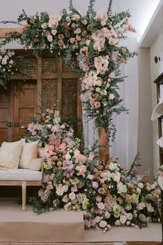 an arrangement of flowers and greenery on display in front of a wooden door at a wedding