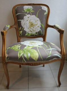 a chair with flowers painted on it sitting in front of a white wall and tiled floor