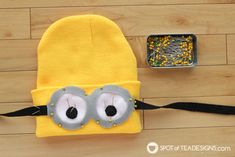 a yellow hat with eyeballs on it next to a metal container filled with beads