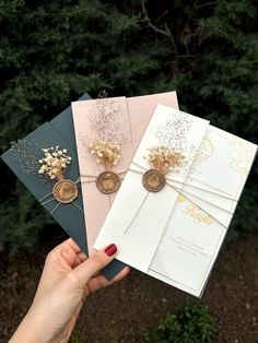 three handmade greeting cards in different colors and designs are held up by a woman's hand