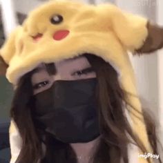 a person with long hair wearing a black mask and a yellow pokemon pikachu hat