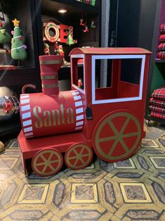 a small red train sitting on top of a floor next to a christmas display case