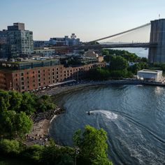 an aerial view of a city and the water with a bridge in the back ground