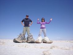 a man and woman standing on top of snow covered ground with their hands in the air