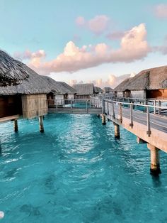 the water is very blue and clear with some huts on each side that are connected by wooden poles