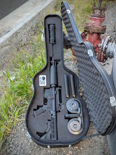 an open guitar case sitting on the ground next to a fire hydrant with tools in it