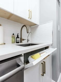 a kitchen with white cabinets and gold handles