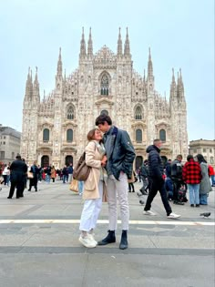 a man and woman standing in front of a cathedral