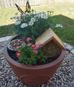 a potted planter filled with flowers and a bird house on top of it