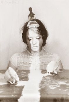 a woman sitting at a table with a brush on her head