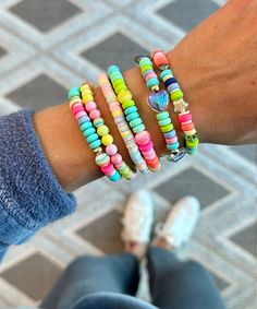 a person wearing colorful bracelets on their arm and holding onto the other hand with two different colored beads