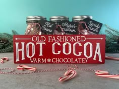 an old fashioned hot cocoa sign with candy canes in front of it on a table