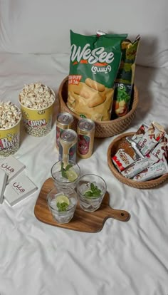 snacks and drinks on a bed with white sheets