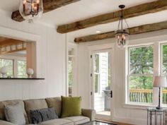 a living room filled with furniture and lots of wood beamed ceiling beams in front of two windows