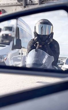 the reflection of a person in a side view mirror on a motorbike with a helmet