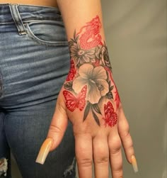 a woman's hand with flowers and butterflies tattooed on her left arm, holding onto the wrist