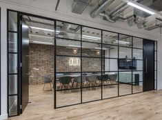 an empty office with glass walls and wooden flooring is pictured in this rendering image