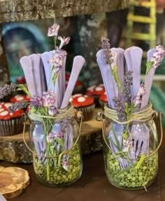 two mason jars filled with purple flowers and cupcakes