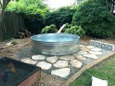 an outdoor hot tub in the middle of a yard with rocks and gravel around it