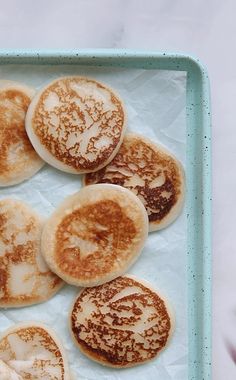 some pancakes are on a blue tray with powdered sugar