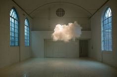 there is a cloud floating in the middle of an empty room with two large windows