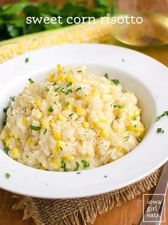 a white bowl filled with corn risottoe on top of a wooden table