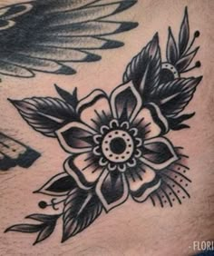 a black and white flower tattoo on the back of a man's stomach, with wings