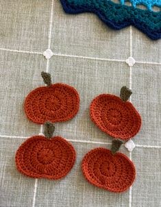 three crocheted pumpkins are hanging on a table