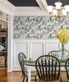 a dining room with blue and white wallpaper, chairs, table and chandelier