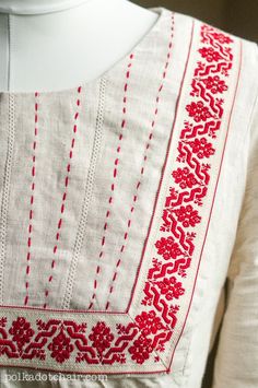 a white dress with red embroidery on it