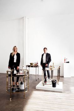 two people standing next to each other in front of a table with drinks on it