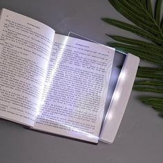 an open book sitting on top of a table next to a plant