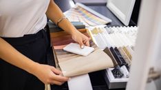 a woman is working on some fabric samples