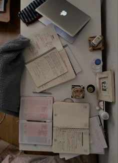 an open laptop computer sitting on top of a desk next to papers and other items