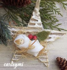 an ornament with a teddy bear in the shape of a star next to pine cones