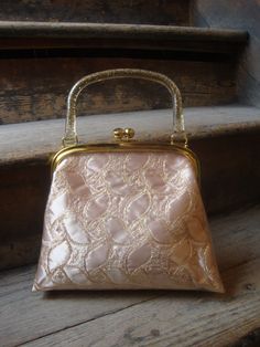 "This is a plastic covered gold and beige brocade purse from the 1950's or early 1960's. It features a gold confetti lucite handle. The gold tone kiss clasp works well. It has a peach pink sateen lined interior. No rips, tears, dirt to tell of. This purse is in great shape! Comes from a smoke free home. Measurements: Length: Bottom: 10\" top: 8\" Height without Handle: 8.5\" with Handle: 12\" Width at Bottom: 3\" Please ask me any questions you may have before buying as this is a final sale. Ple Vintage Embroidered Evening Bag For Party, Vintage Gold Embroidered Evening Bag, Gold Vintage Embroidered Evening Bag, Vintage Wedding Bags With Gold Embroidery, Gold Vintage Bag For Events, Vintage Gold Evening Bag For Wedding, Gold Embroidered Evening Bag For Events, Vintage Beige Evening Bag For Party, Vintage Beige Evening Bag For Wedding