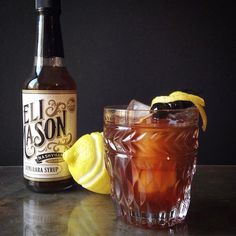 a bottle of booze next to a glass filled with ice and lemon