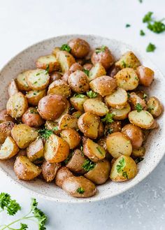 a white bowl filled with potatoes and parsley