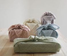 four different colors of blankets sitting on top of a wooden table