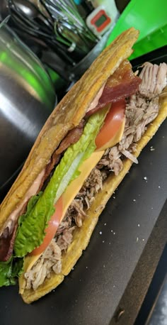 a sandwich with meat, lettuce and tomato on it sitting on a counter