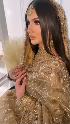 a woman with long hair wearing a gold dress and headdress is posing for the camera