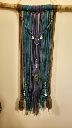 a wall hanging with beads and tassels attached to it's sides in a room