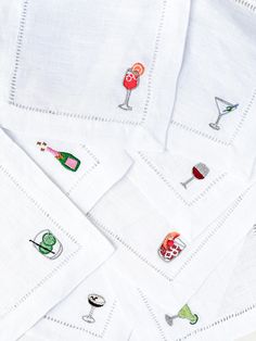 several embroidered napkins with wine glasses and drinks on them, all in different colors