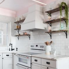 a white kitchen with open shelving above the stove