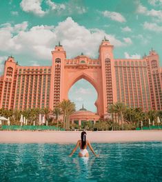 a woman sitting in the middle of a body of water next to a large building