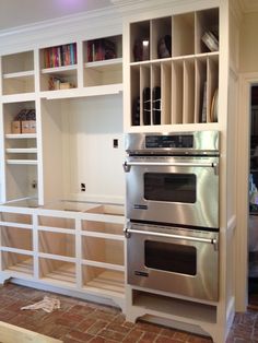 a kitchen with white cabinets and stainless steel stove top oven in front of built - in bookcases