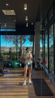 a woman is standing in the middle of a room with mirrors and exercise equipment on the walls